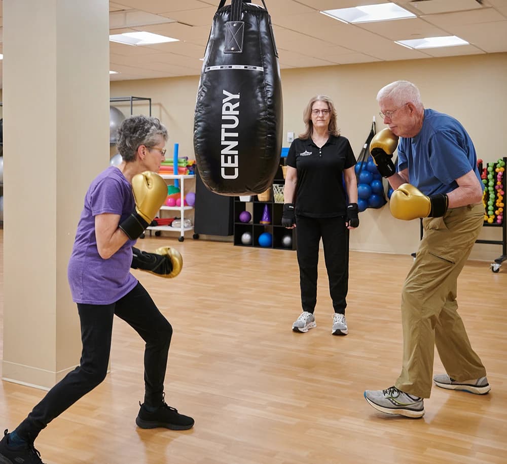 Man and woman hitting boxing bag